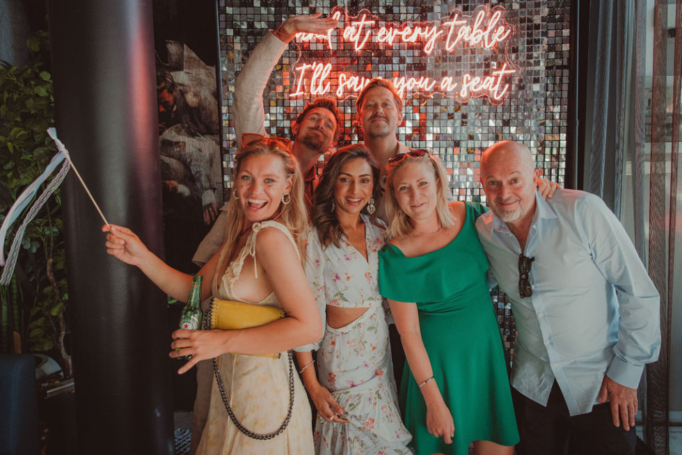 Glada gäster poserar med roliga rekvisita i en fotohörna under en bröllopsfest.