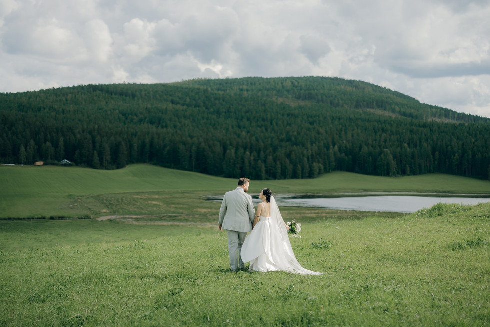 ett brudpar på en äng vid vattnet