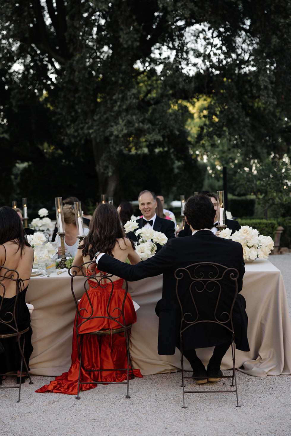 Ett sällskap av nära och kära delar ett skratt vid ett bröllopsbord.