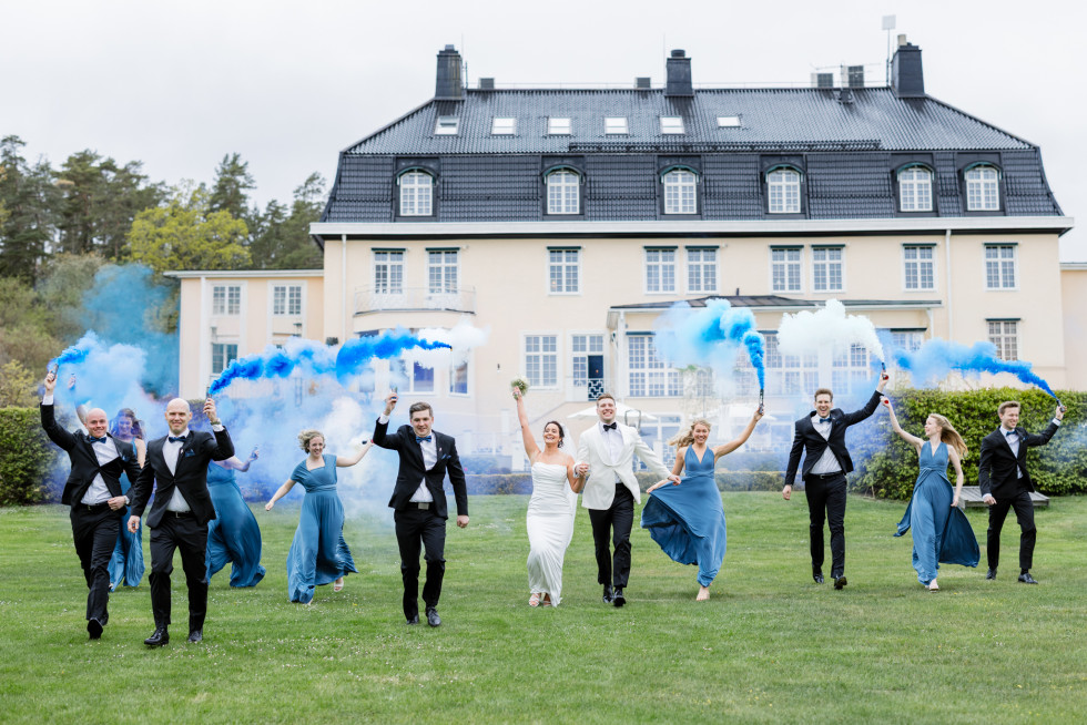 Brudpar och gäster med färggranater framför ett slott – kreativa bröllopsbilder med färgrök"