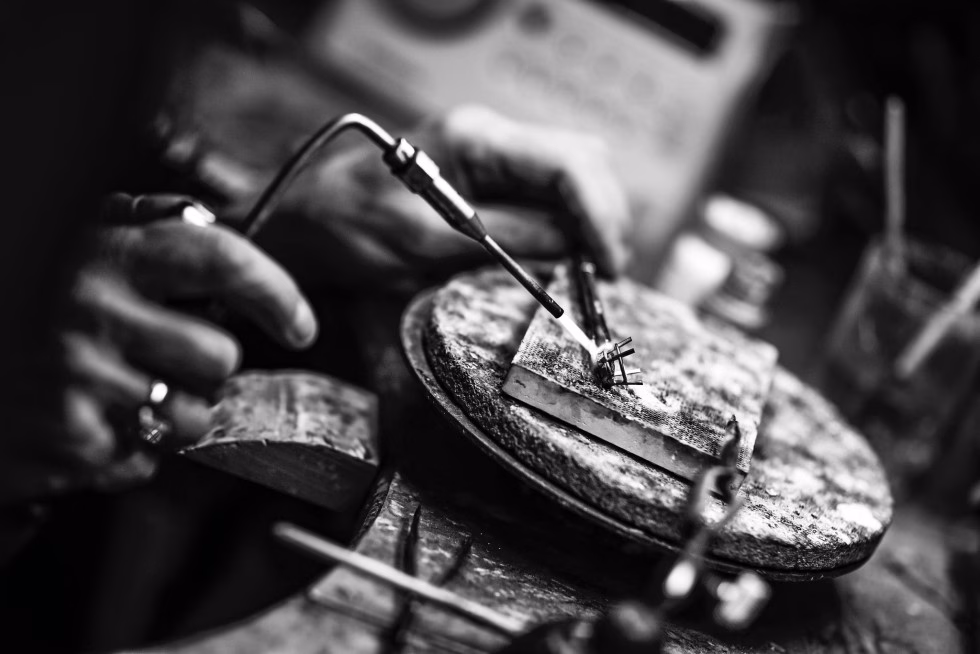 Gullsmed som arbeider med å forme en håndlaget giftering – et unikt håndverk i skapelsen av personlige smykker.