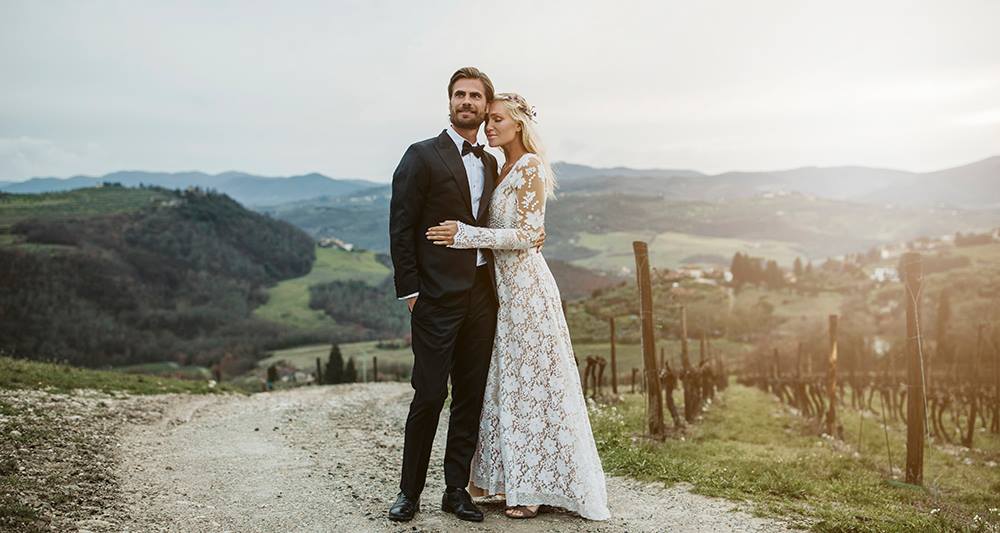 Tailor Store – Måttsydd bröllopskostym med perfekt passform för brudgummen bredvid sin brud.