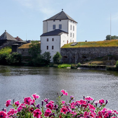 Vy över Nyköpingshus historiska slottsbyggnad med de vita tornen intill Nyköpingsån.