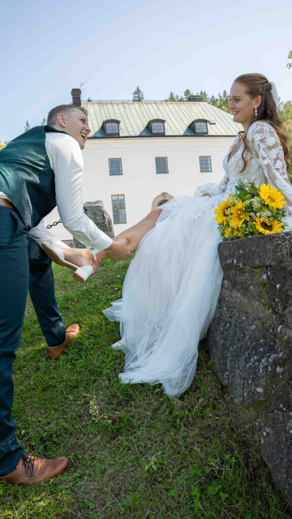 brudgum sätter på skon på bruden, videograferna
