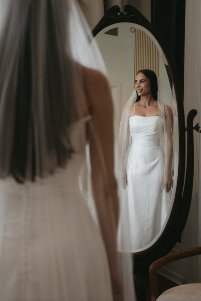 Inspiration: Modern Wedding Rules för brudklänning. En brud i vit klänning ser sin spegelbild inför en modern vigsel.