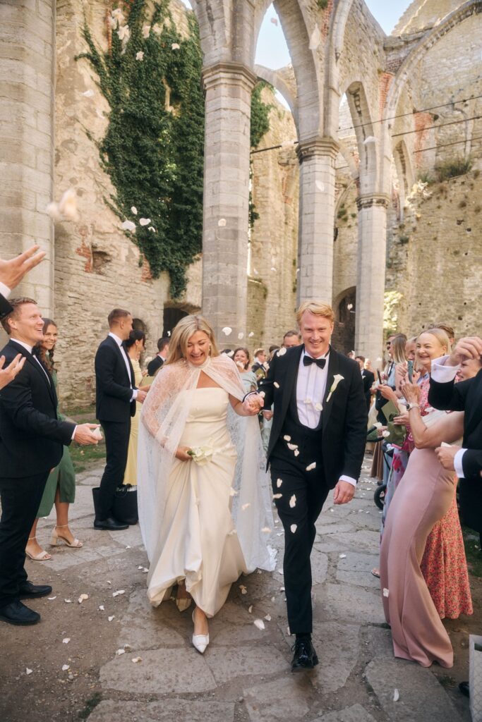 Ett nygift par kramar om varandra i en historisk medeltida kyrkoruin i Visby under ett bröllop på Gotland