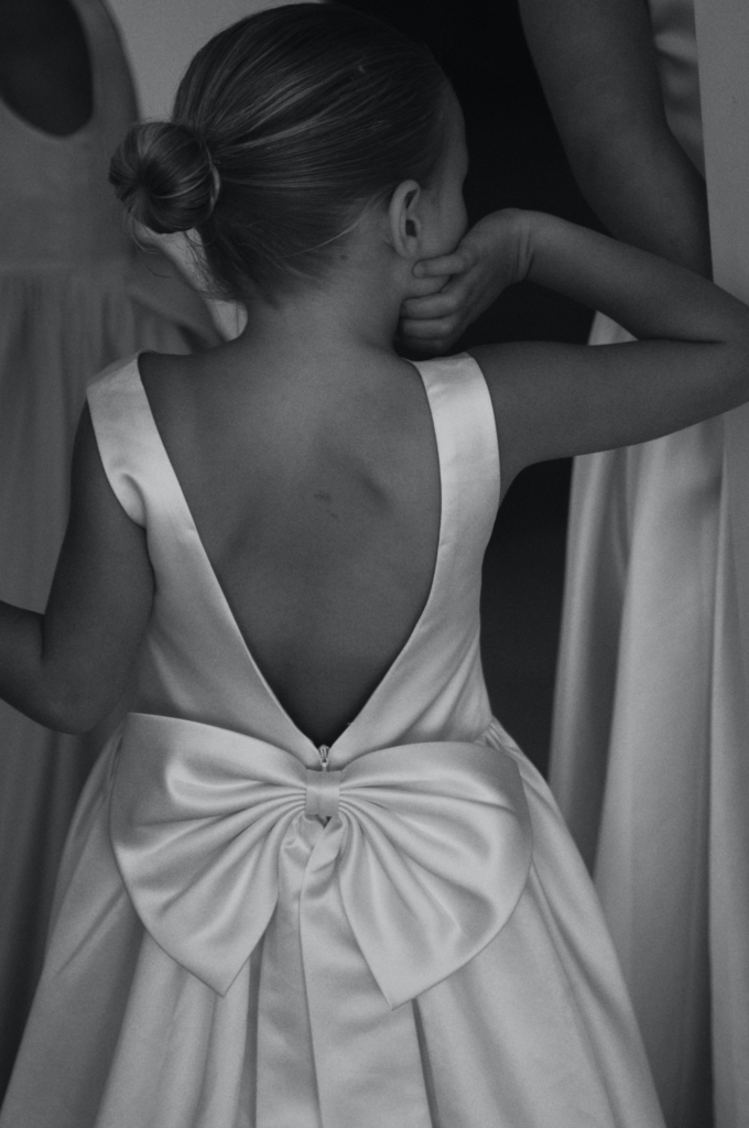 En liten jente i hvit kjole som brudepike, klar for barn i bryllup.